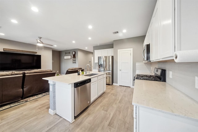 kitchen featuring white cabinetry, sink, stainless steel appliances, a center island with sink, and light wood-type flooring