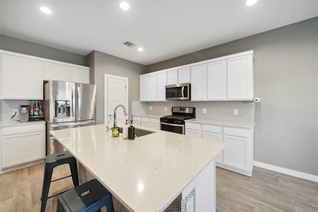 kitchen featuring a center island with sink, white cabinets, stainless steel appliances, and sink