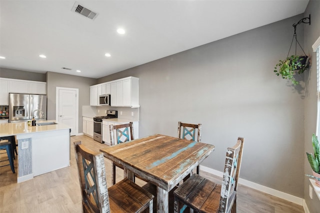 dining space featuring sink and light hardwood / wood-style floors