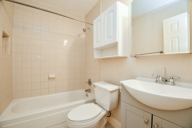 full bathroom featuring vanity, a textured ceiling, toilet, and tiled shower / bath