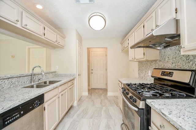 kitchen with sink, decorative backsplash, light stone countertops, a textured ceiling, and stainless steel appliances