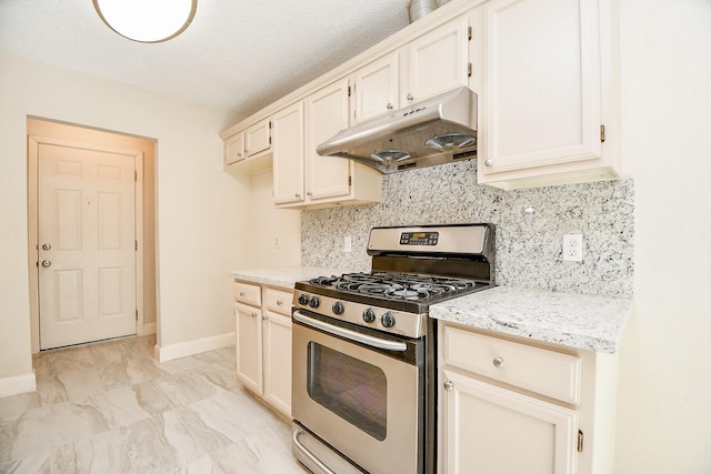 kitchen featuring gas stove, light stone counters, a textured ceiling, and tasteful backsplash