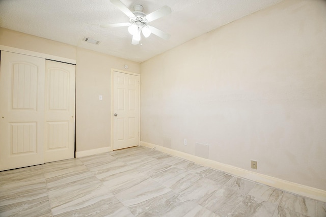 unfurnished bedroom with ceiling fan, a textured ceiling, and a closet