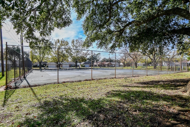 view of tennis court featuring a lawn