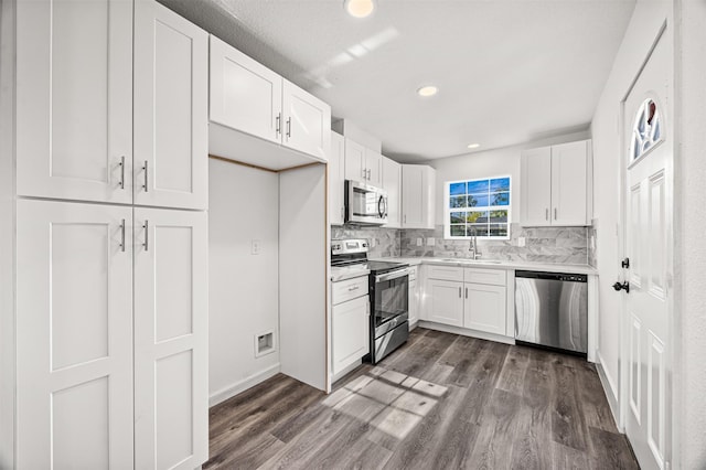 kitchen with tasteful backsplash, sink, white cabinets, and appliances with stainless steel finishes