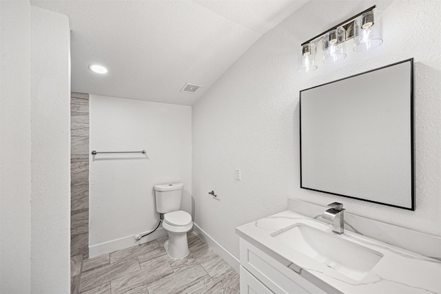 bathroom featuring a textured ceiling, vanity, lofted ceiling, and toilet