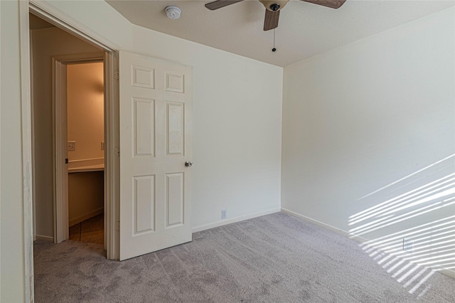 unfurnished bedroom with a walk in closet, ceiling fan, a closet, and light carpet