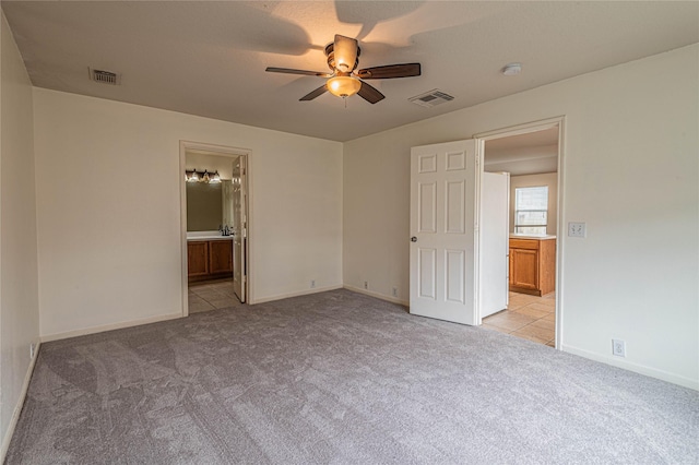 unfurnished bedroom with ensuite bath, ceiling fan, and light carpet