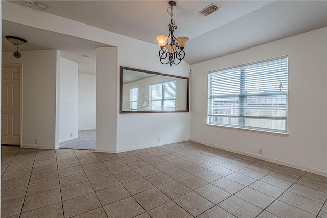 tiled empty room with lofted ceiling and a notable chandelier