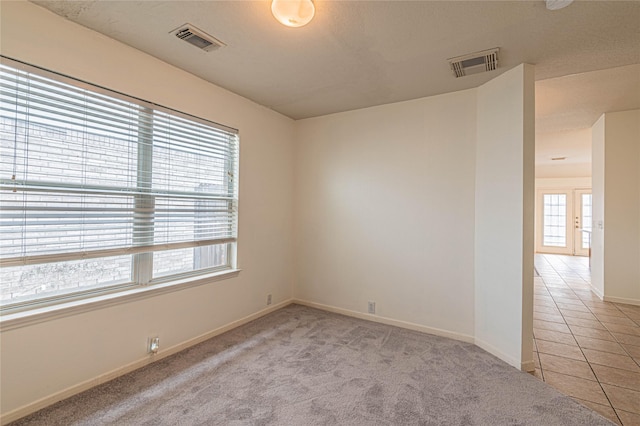 empty room with a healthy amount of sunlight and light tile patterned flooring