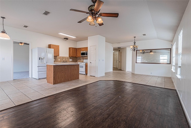 kitchen with vaulted ceiling, hanging light fixtures, white appliances, and light wood-type flooring