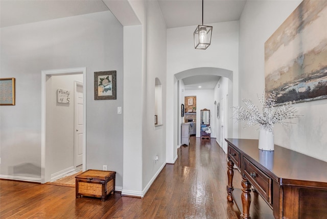 hall with a towering ceiling and dark hardwood / wood-style floors