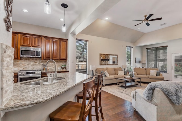 kitchen featuring pendant lighting, backsplash, sink, appliances with stainless steel finishes, and a breakfast bar area