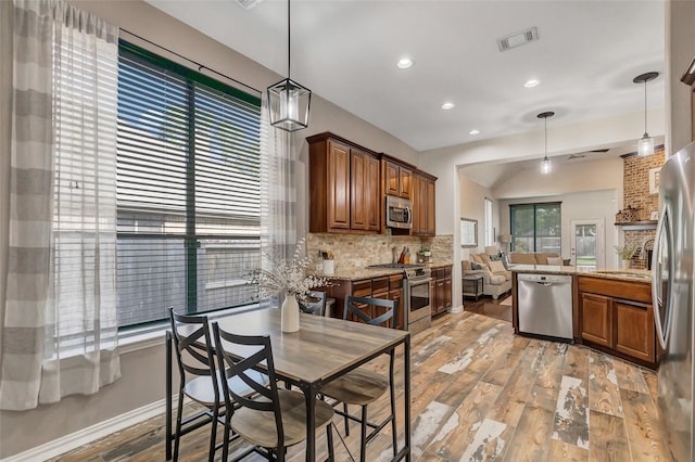 kitchen with light hardwood / wood-style flooring, decorative backsplash, light stone countertops, decorative light fixtures, and stainless steel appliances