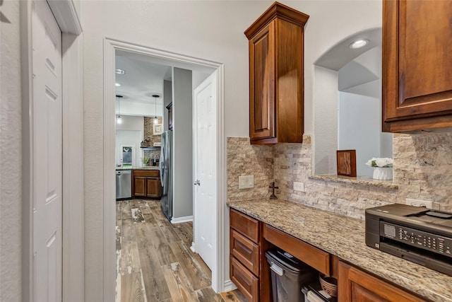 kitchen featuring hardwood / wood-style flooring, decorative backsplash, light stone countertops, and appliances with stainless steel finishes