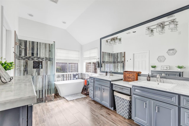 bathroom with a tub, vanity, and lofted ceiling