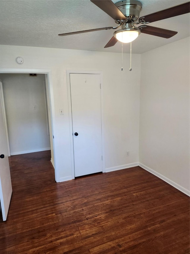 unfurnished bedroom with ceiling fan, dark hardwood / wood-style floors, and a textured ceiling