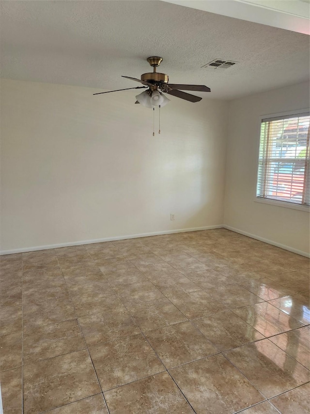 empty room with light tile patterned floors, a textured ceiling, and ceiling fan