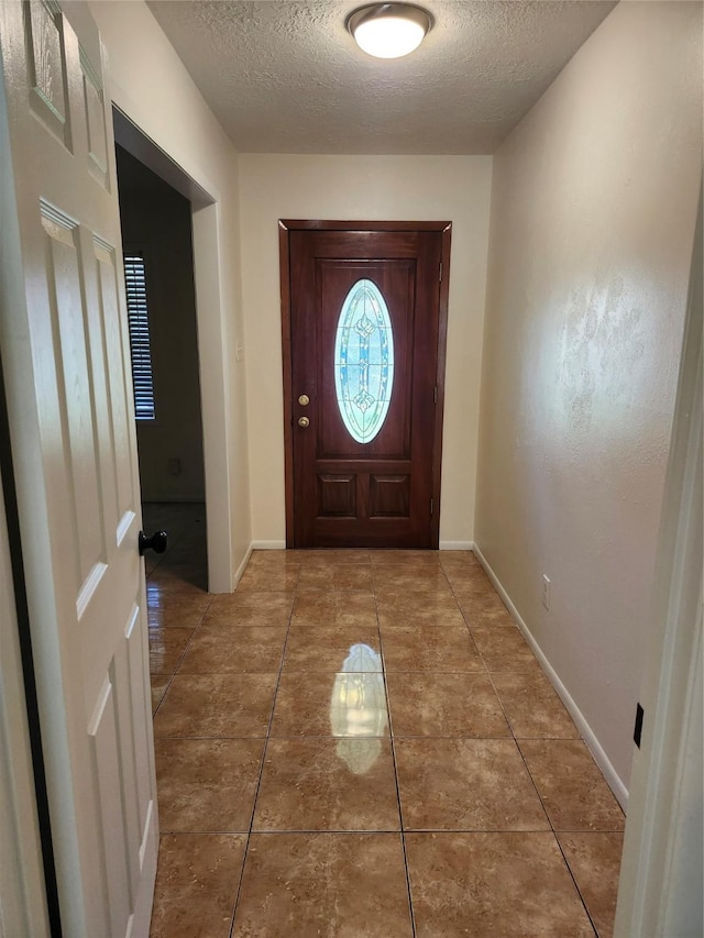 doorway with tile patterned floors and a textured ceiling