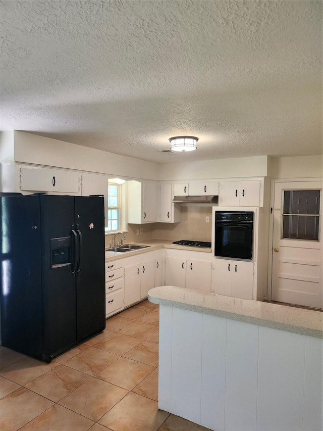 kitchen with sink, light tile patterned floors, a textured ceiling, white cabinets, and black appliances