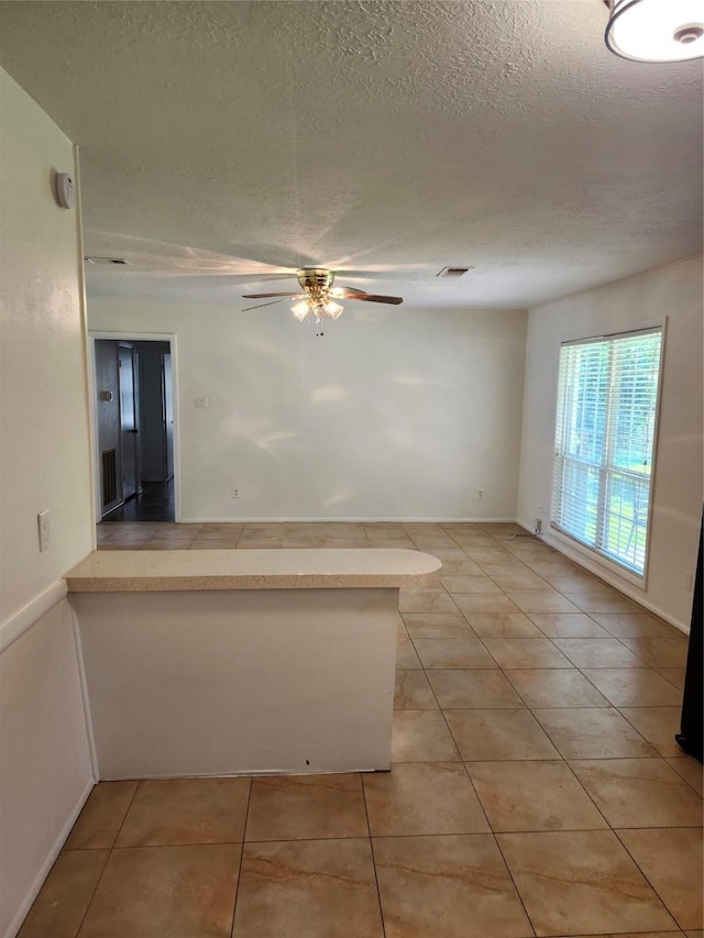 tiled empty room with a textured ceiling and ceiling fan