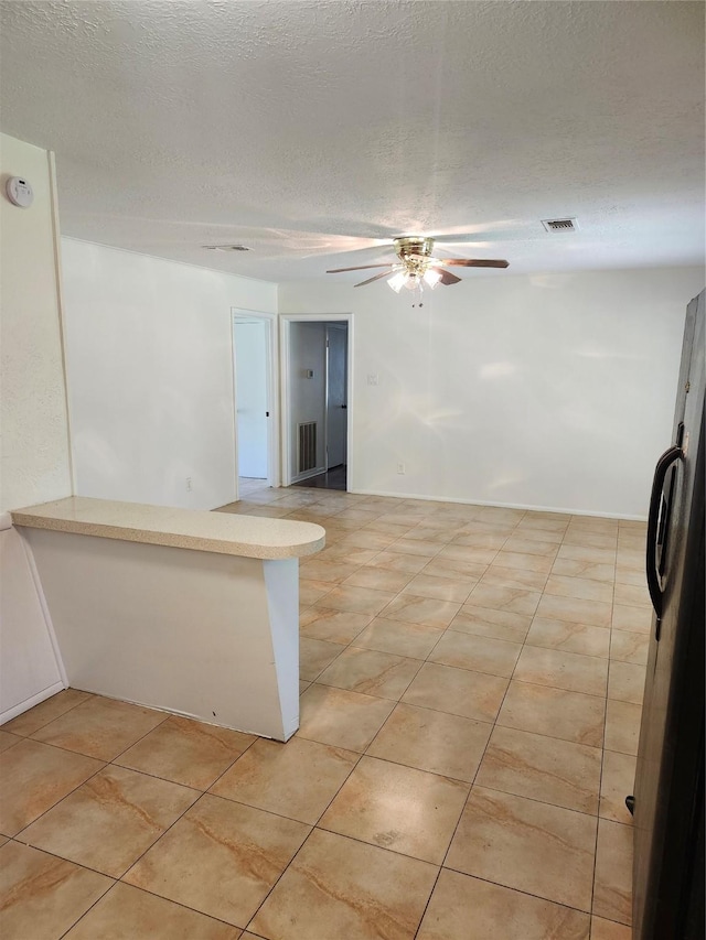 empty room featuring ceiling fan, light tile patterned flooring, and a textured ceiling