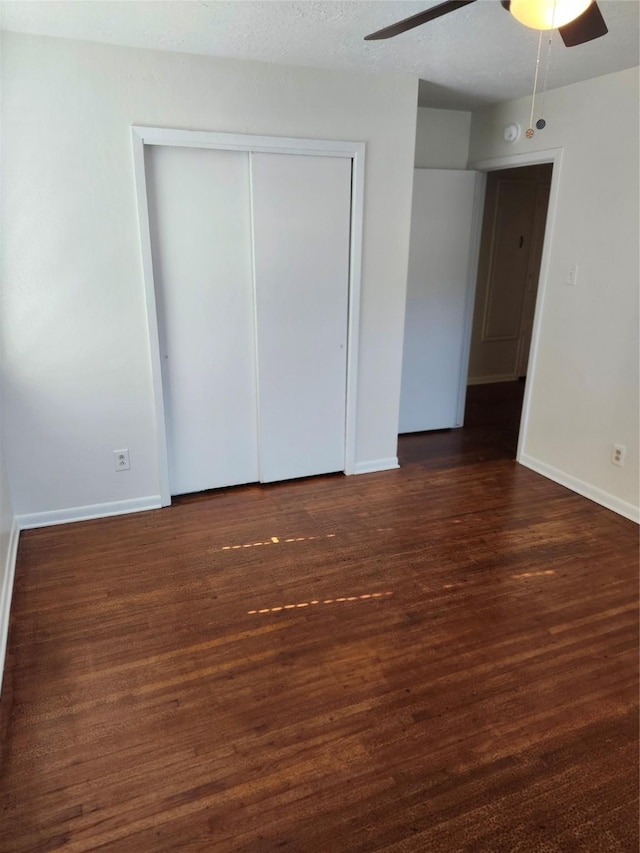 unfurnished room featuring a textured ceiling, ceiling fan, and dark wood-type flooring