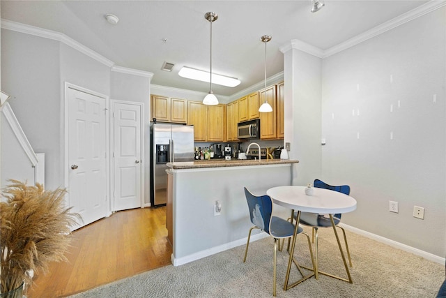 kitchen with kitchen peninsula, appliances with stainless steel finishes, light brown cabinets, decorative light fixtures, and ornamental molding