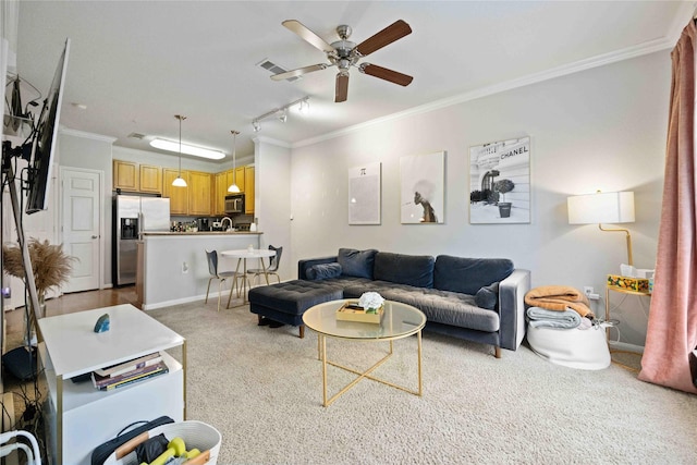 living room featuring ceiling fan, light colored carpet, crown molding, and track lighting