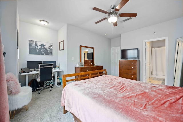 bedroom featuring ceiling fan, light colored carpet, and ensuite bath