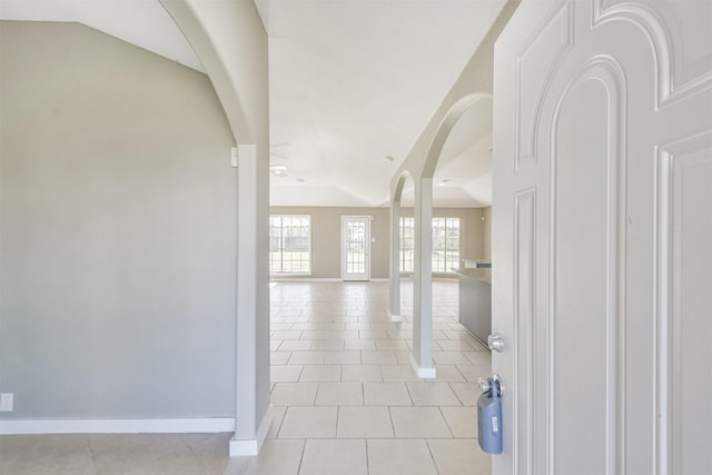 corridor featuring light tile patterned floors and vaulted ceiling