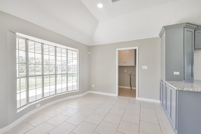 tiled empty room featuring lofted ceiling