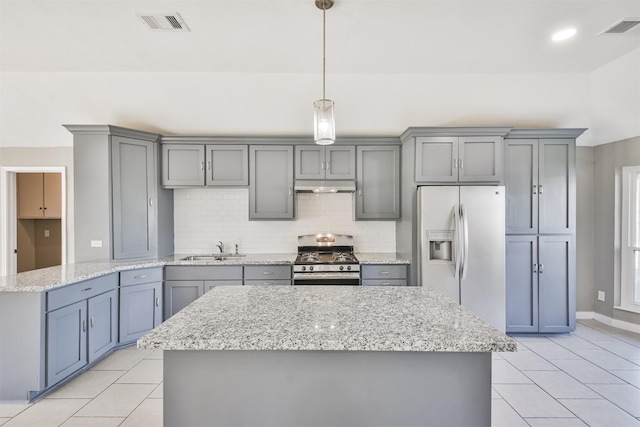 kitchen with sink, a center island, stainless steel appliances, decorative light fixtures, and decorative backsplash