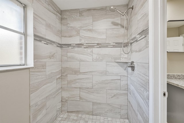 bathroom featuring a tile shower, vanity, and a healthy amount of sunlight