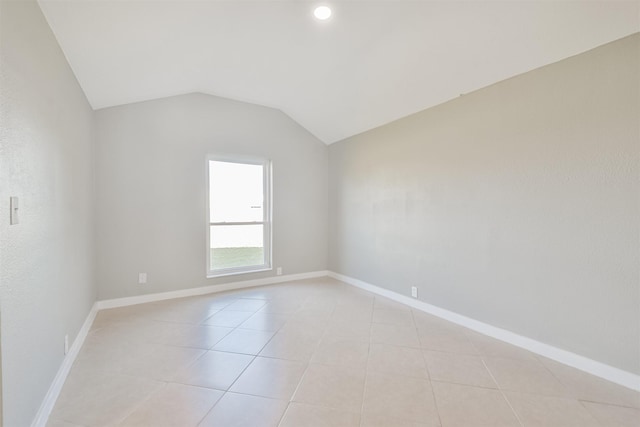 unfurnished room with light tile patterned floors and vaulted ceiling