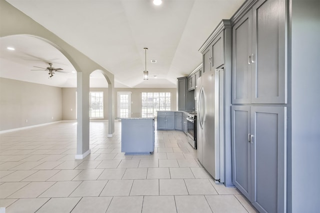 kitchen with light stone countertops, stainless steel appliances, ceiling fan, hanging light fixtures, and lofted ceiling