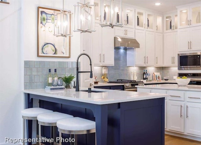 kitchen featuring sink, a kitchen breakfast bar, pendant lighting, white cabinets, and appliances with stainless steel finishes