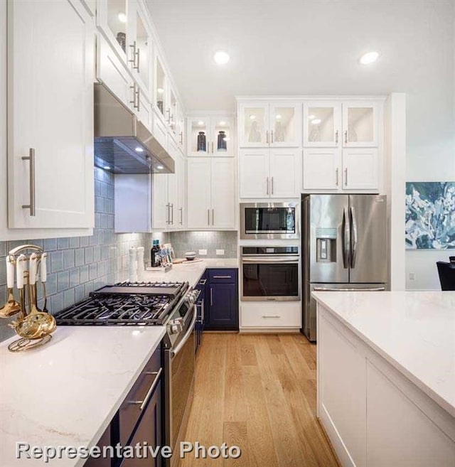 kitchen with white cabinets, stainless steel appliances, and light stone counters