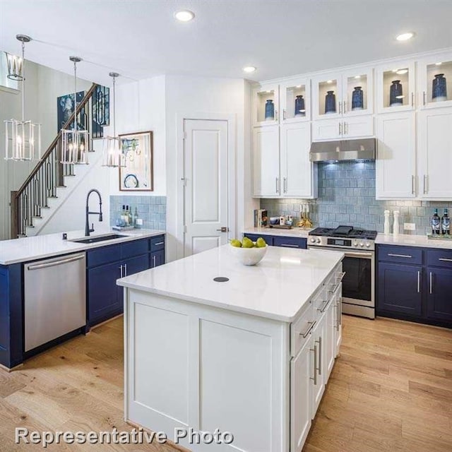 kitchen with sink, a kitchen island, white cabinets, and appliances with stainless steel finishes