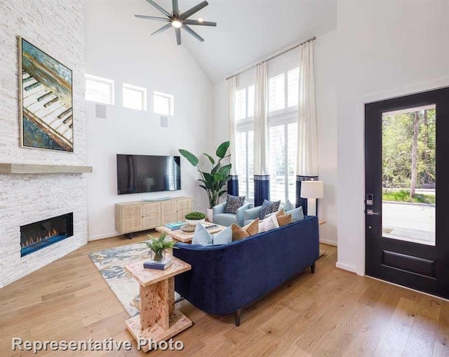 living room featuring a fireplace, ceiling fan, plenty of natural light, and a towering ceiling