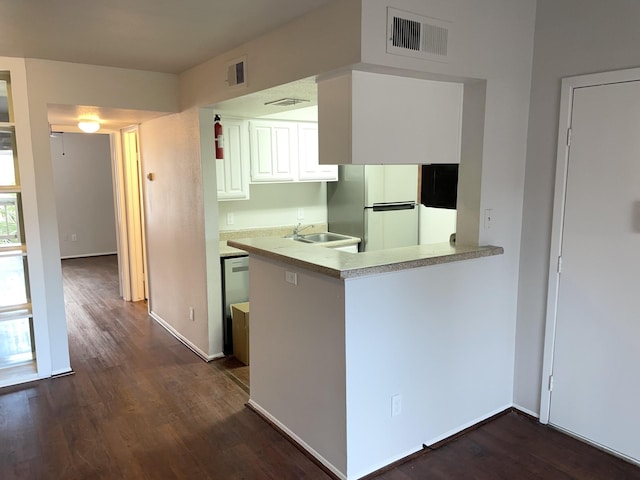 kitchen featuring dark hardwood / wood-style floors, refrigerator, white cabinetry, and kitchen peninsula