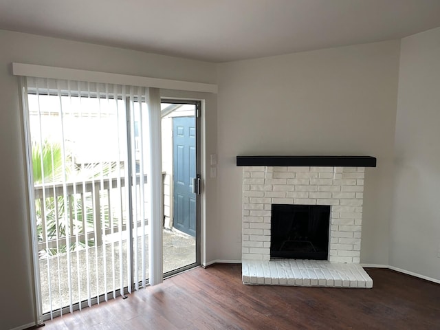 unfurnished living room featuring hardwood / wood-style floors and a brick fireplace