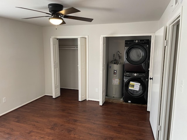 laundry area featuring water heater, stacked washer and dryer, ceiling fan, and dark wood-type flooring