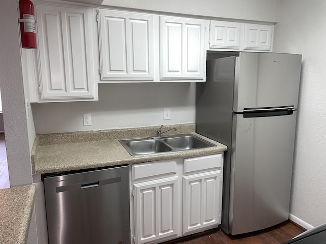 kitchen with dark hardwood / wood-style flooring, stainless steel appliances, white cabinetry, and sink