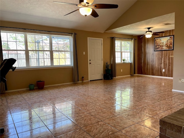 unfurnished room featuring wooden walls, ceiling fan, and a healthy amount of sunlight