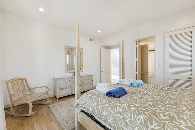 bedroom featuring light hardwood / wood-style floors, ensuite bath, and a closet