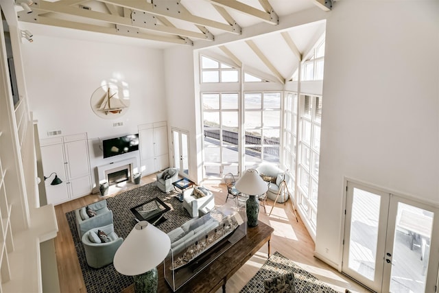 living room with beam ceiling, french doors, high vaulted ceiling, and light hardwood / wood-style flooring