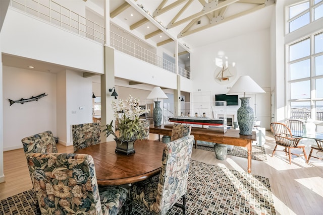 dining area with light hardwood / wood-style floors and a towering ceiling