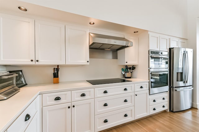 kitchen with white cabinets, stainless steel appliances, extractor fan, and light hardwood / wood-style floors