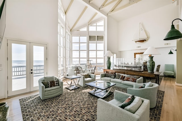 living room with beamed ceiling, french doors, light hardwood / wood-style flooring, and high vaulted ceiling